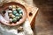 Dyed quail easter eggs in a rustic red brown plate. Easter mood card, copyspace. Beige linen towel, feather, alder cones