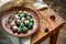 Dyed quail easter eggs in a rustic red brown plate. Easter mood card, copyspace. Beige linen towel, feather, alder cones