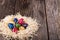 Dyed quail eggs in a nest on wooden background.