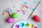 Dyeing easter eggs. Paints in palette, colorful eggs and child palm print on table, flat lay