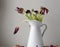 Dying dark red tulips in white jug close up