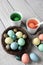 Dying Easter Eggs. Cups filled with dye and a birds nest filled with colored chicken and quail eggs on a rustic farmhouse style