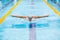 Dynamic and fit swimmer in cap breathing performing the butterfly stroke