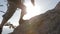 Dynamic following close-up shot of a man climbing a mountain. Detail of mountaineering boots and adventurous man