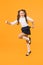 She is dynamic. Happy energetic schoolchild in motion on yellow background. Little girl with long hair feeling energetic