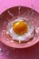Dynamic High Speed Photography of Fresh Egg Splashing in Pink Bowl on Vibrant Pink Background