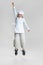 Dynamic image of little cute girl in white cook uniform and huge chef& x27;s hat jumping isolated on white studio background.