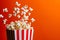Dynamic image of popcorn flying out of a classic red and white striped box on an orange background
