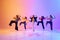 Dynamic image of talented, artistic teen girls dancing hip hop against gradient studio background in neon light