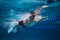 Dynamic image of young guy, swimming athlete in red cap and goggles in motion in swimming pool, training. Freestyle swim