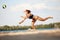 Dynamic image of young woman in motion, playing beach volleyball, hitting ball and falling down on sand