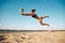 Dynamic image of young woman in motion, playing beach volleyball, hitting ball and falling down on sand