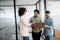 In a dynamic office setting, a businesswoman discusses on-the-go with two male colleagues