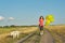 Dynamic outdoor portrait of running girl with white dog and yellow balloons