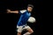 Dynamic portrait of school age boy, junior male rugby player practicing rugby football isolated on dark background with