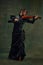 Dynamic pose of passionate female musician, young woman, violinist in black attire, playing violin with intense