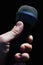 Dynamic professional microphone for vocal and instruments held in man left hand against dark background.