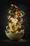 Dynamic shot of fresh salad, vegetables fall into a porcelain bowl.