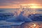 A dynamic shot of water splashing onto the shore of a beach as the sun sets in the background, A freeze-frame of ocean wave at the