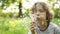 Dynamic video. A boy is blowing on a dandelion. Flower seeds scatter in the wind. Summer vacation. Family holiday