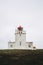 Dyrholaey lighthouse under heavy gray sky.