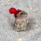 Dzungarian little hamster in a red Christmas hat on a gray knitted blanket, decorated with New Year`s garlands. Close-up