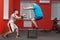 Eager overweight man is doing jumping in the gym under the guidance of a personal trainer