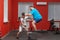 Eager overweight man is doing jumping in the gym under the guidance of a personal trainer