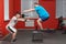 Eager overweight man is doing jumping in the gym under the guidance of a personal trainer