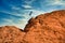 Eagle flies from nest above western red rock against clouded sky