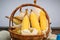 Ear of corn, revealing yellow kernels, photo of maize in a wicker basket