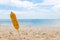 Ear of fried corn on a stick. Stuck in the sand on a tropical beach. Close-up. Sea and blue sky on background