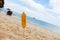 Ear of fried corn on a stick. Stuck in the sand on a tropical beach. Close-up. Sea and blue sky on background