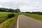 Early autumn rolling rural landscape with curving road, meadows and forest