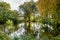 Early autumn view of a pond surrounded by autumnal coloured trees.buret through the trees..