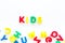 Early childhood development concept. Word kids written by plastic letters of toy alphabet on white background top view