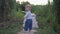 Early childhood, joyful infant boy walking on wooden bridge barefoot in nature among the green grass