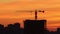 Early dawn - morning sky of red and orange shades - silhouettes of buildings and lifting crane