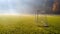 Early morning in the amatuer soccer field. Football game playground in autumn foggy morning. Sunlight in the background