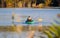 In the early morning, a fisherman sits in a boat in the middle of the lake and catches fish