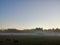 Early morning on the outskirts of the village with a clear cloudless sky and fog on the edge of the forest