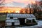 Early morning snowy barn with a vibrant orange sunrise behind it.