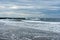 Early morning stormy sky and oceans with waves crashing on the jetty