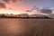 Early morning sunrise of the beach at low tide with palmetto trees in the background.