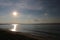 The early morning sunshine and the ocean waves hit the long sandy beach with blue clouds and white sand