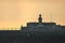 Early morning view of red East Pier lighthouse against epic hazy orange sky with adult running and exercising in Dun Laoghaire