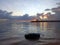 Early morning view with sunrise over the sea with calm wave water. Natural background of the beach with a tire as foreground