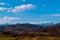 Early spring hills with snow covered mountain tips in the background