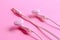 Earphone, white in ear headphones on a light pink background.