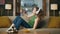 Earphones woman listening music laying sofa at flat. Relaxed girl sitting couch